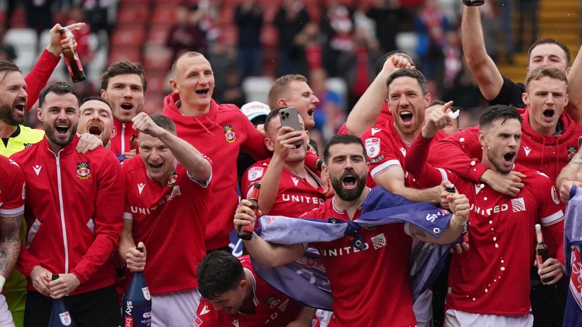 Wrexham players on the pitch celebrating promotion to League One after the final whistle. Jacob King/PA Images/Getty Images